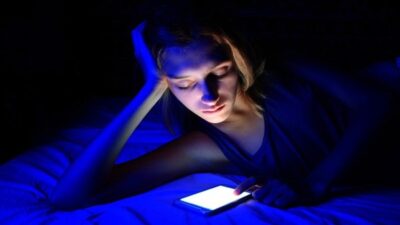 Cô gái đang xem điện thoại trong điều kiện thiếu ánh sáng