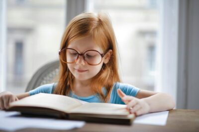 hình ảnh bé gái đeo kính đọc sách