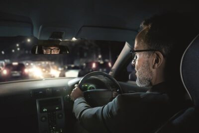 người đàn ông đeo kính đang lái xe vào ban đêm