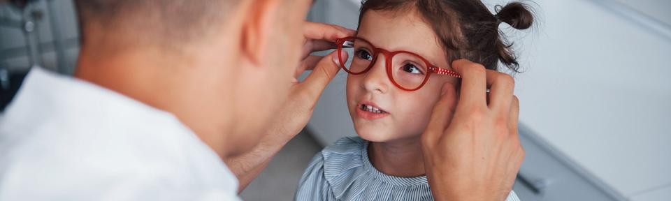 Bác sĩ đang đeo kính cận cho bé gái