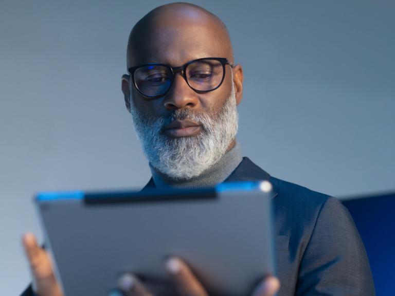 người đàn ông đeo tròng kính Zeiss BlueGuard đang nhìn vào màn hình iPad