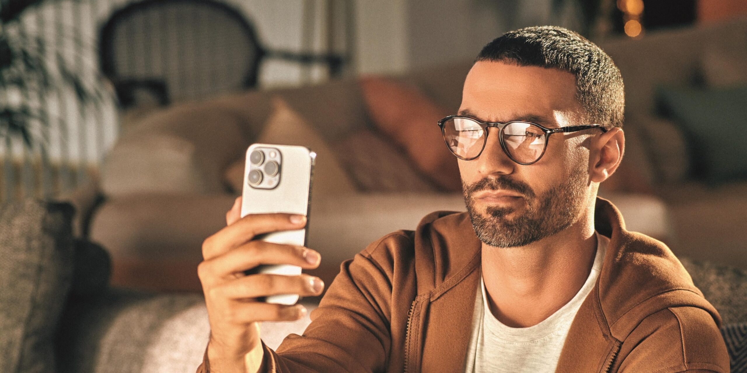 người đàn ông đeo tròng kính Essilor đang cầm điện thoại